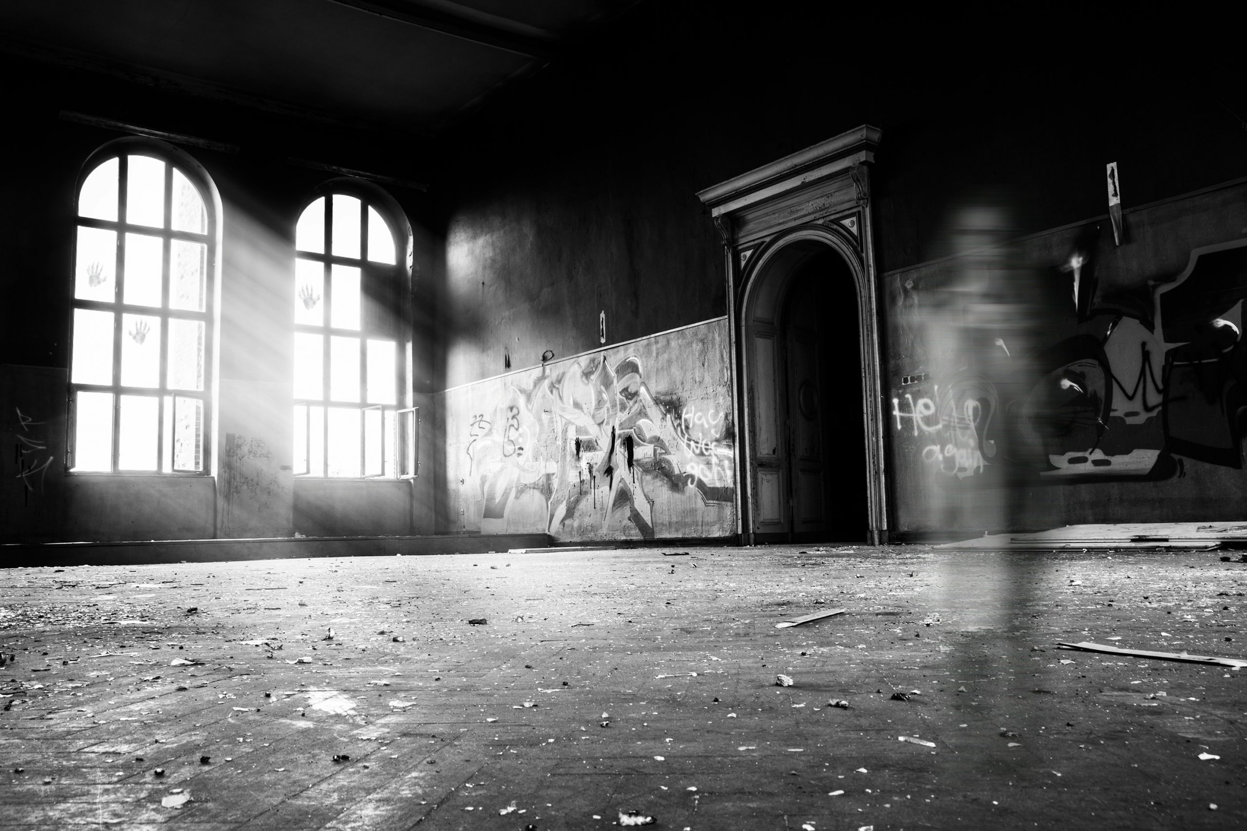 Graustufenfoto einer verwaschenen Person, die in einem verlassenen Gebäude steht